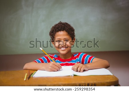 Portrait of cute little boy writing book in classroom