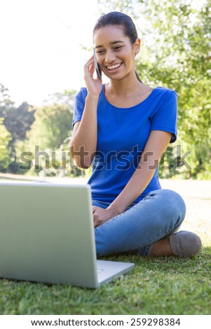 Woman using phone in park on a sunny day