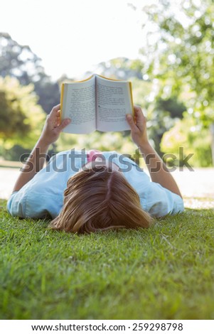 Pretty woman reading book in park on a sunny day