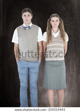 Unsmiling geeky hipsters looking at camera against black background
