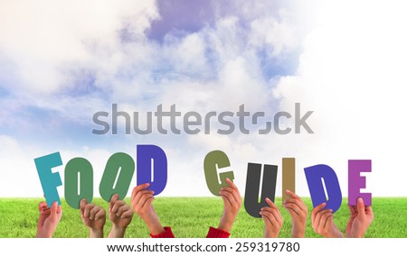 Hands holding up food guide against green field