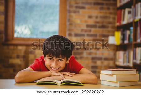 Portrait of cute little boy reading book in the library