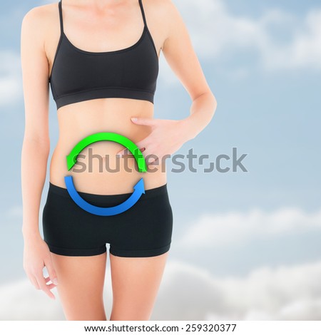 Closeup mid section of a fit woman with hand on stomach against cloudy sky
