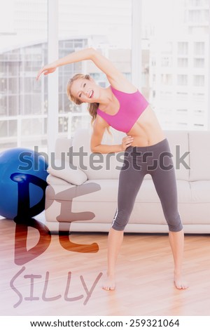 Fit blonde smiling at camera while stretching against be silly
