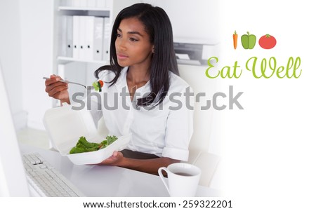 The word eat well against pretty businesswoman eating a salad at her desk