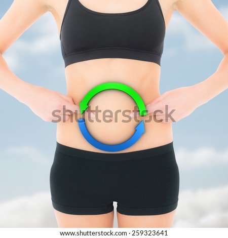 Closeup mid section of a fit woman with hands on stomach against cloudy sky