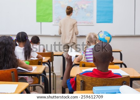 Naughty pupil about to throw paper airplane in class at the elementary school