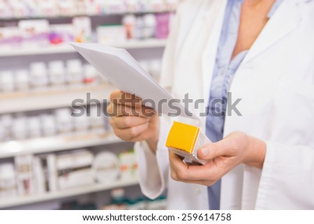 Pharmacist looking at prescription and medicine in the pharmacy