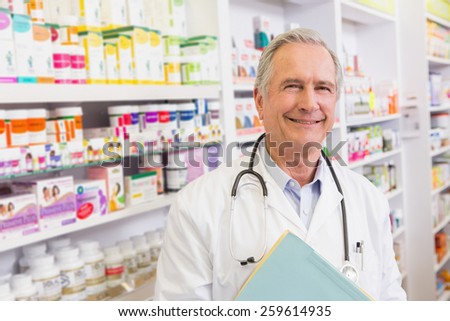 Smiling doctor with stethoscope holding notebooks in the pharmacy
