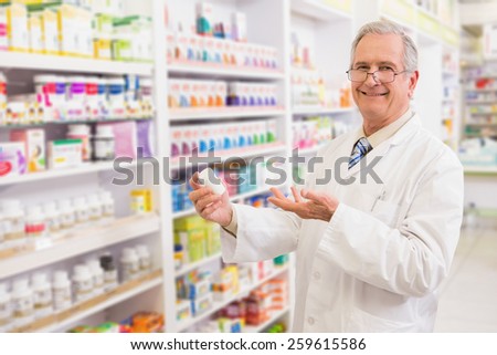 Smiling senior pharmacist showing medication in the pharmacy