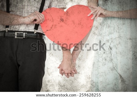 Hipster couple holding heart card against grey background