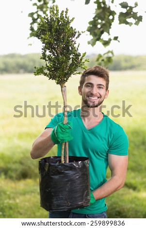 Happy young man gardening for the community on a sunny day