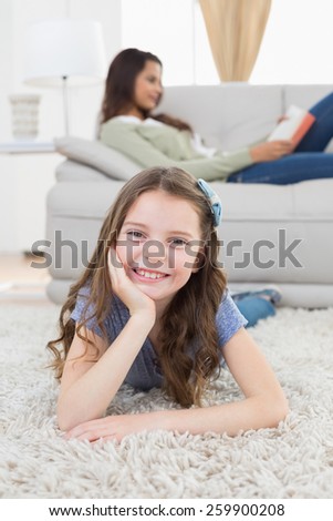 Portrait of happy girl lying on rug while mother relaxing at home