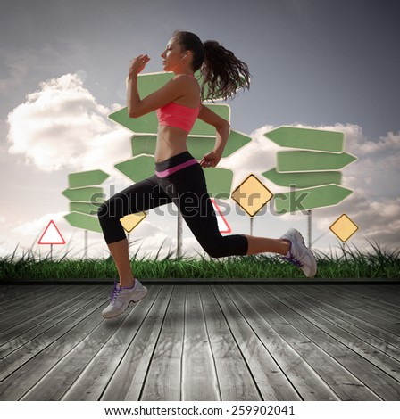 Full length of healthy woman jogging against road signs over wooden planks