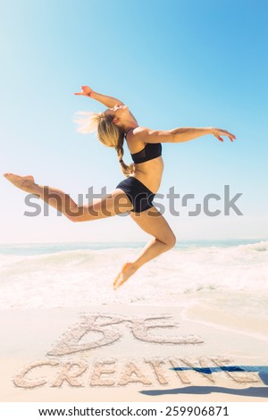Fit blonde jumping gracefully on the beach against be creative