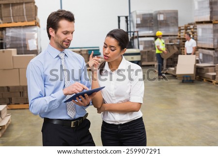 Focused warehouse managers working together in a large warehouse