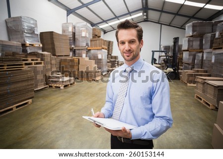 Portrait of smiling manager holding clipboard in warehouse