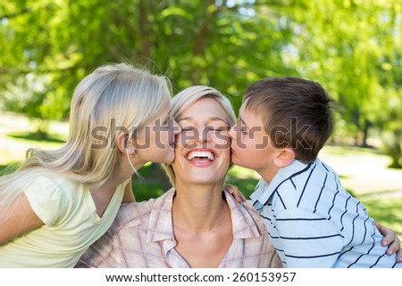 Sister and brother kissing their mother on a sunny day