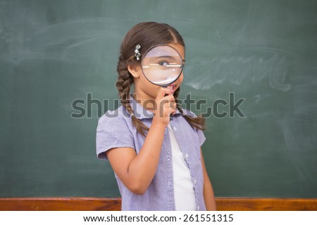 Pupil looking camera with magnifying glass at elementary school