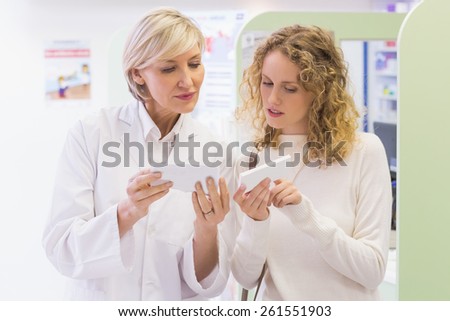 Pharmacist holding a bottle of drugs talking to customer in the pharmacy