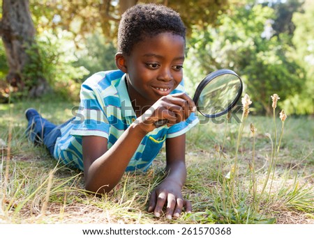 Cute little boy looking through magnifying glass on a sunny day