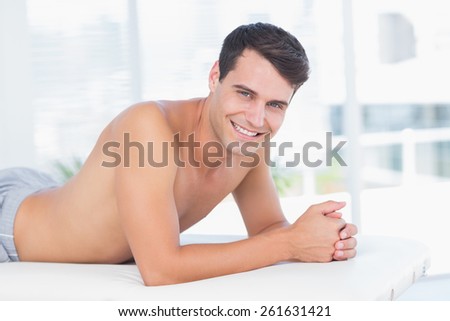 Smiling patient lying on massage table and looking at camera in medical office
