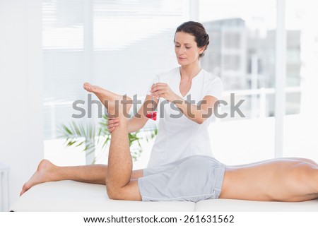 Physiotherapist using reflex hammer in medical office