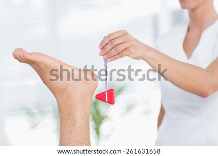 Physiotherapist using reflex hammer in medical office
