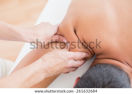 Physiotherapist doing shoulder massage to her patient in medical office