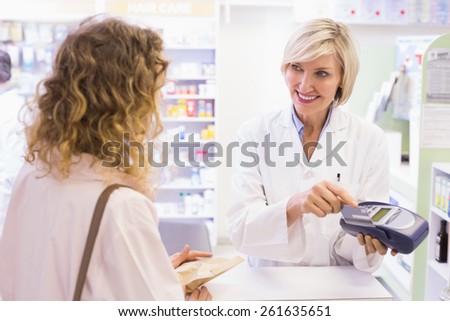 Pharmacist using card machine at pharmacy