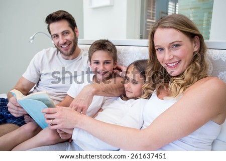 Happy family on the bed reading book at home in bedroom