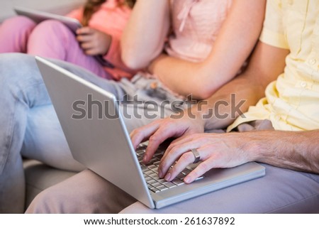 Family on couch using tablet pc and laptop at home in the living room