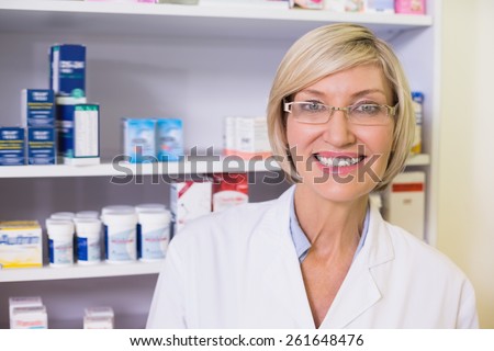 Smiling pharmacist in lab coat looking at camera in the pharmacy