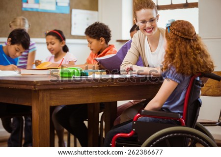 Teacher helping a disabled pupil at the elementary school