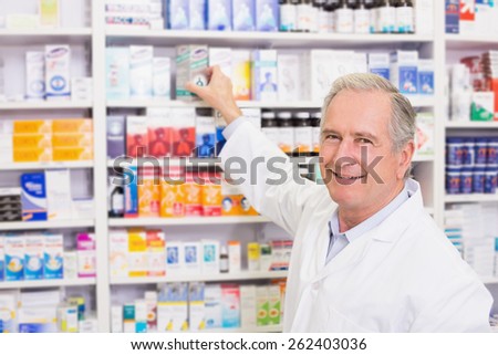 Smiling pharmacist taking medicine from shelf in the pharmacy