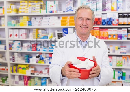 Senior pharmacist holding bowl of medicines at hospital pharmacy