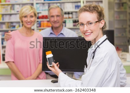 Pharmacist showing medicine jar to a customer at pharmacy