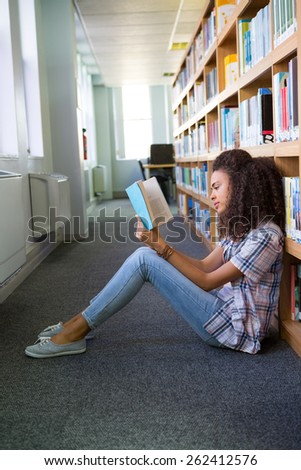 Student sitting on floor in library reading at the university