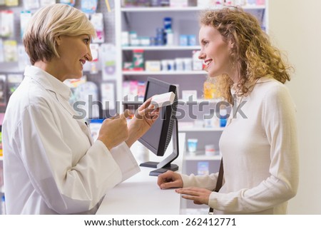 Pharmacist holding medicine box talking to customer in the pharmacy