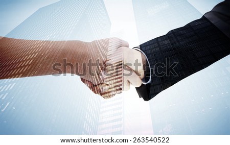 Close up of a handshake against low angle view of skyscrapers