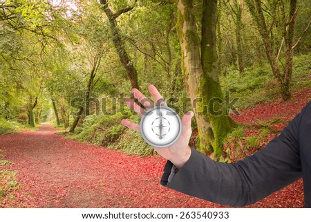 businessman holding hand out in presentation in the forest