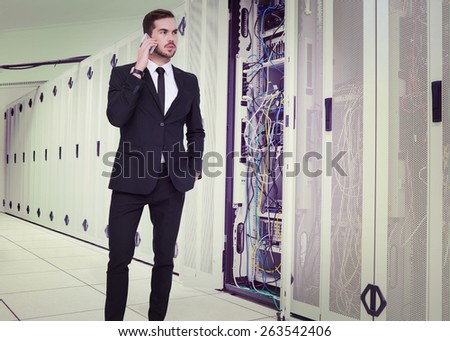 Serious businessman hand in pocket phoning against data center