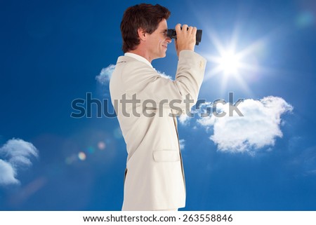 Businessman using binoculars against sky