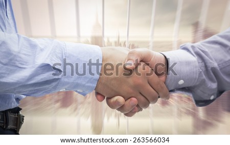 Two men shaking hands against room with large window looking on city