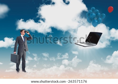 Businessman looking through binoculars against blue sky