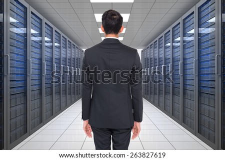 Businessman turning his back to camera against server hallway