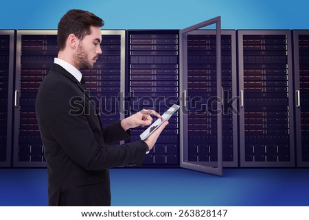 Concentrated businessman touching his tablet against server towers