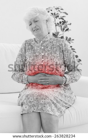 Elderly woman suffering with a belly pain in the living room