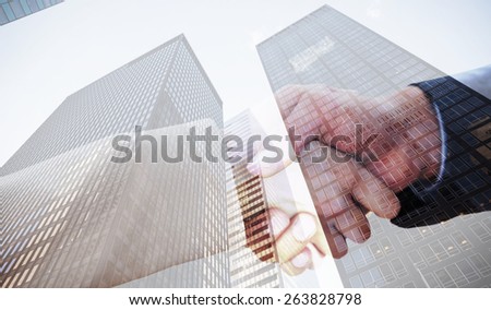 Close up on partners shaking hands against skyscraper