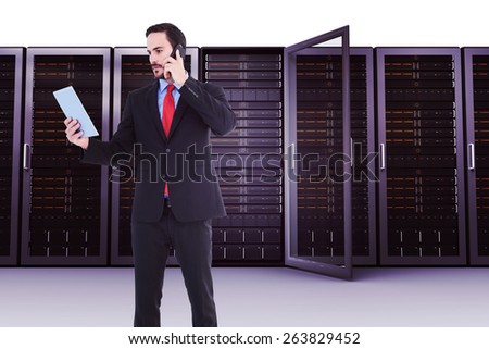 Businessman talking on phone holding tablet pc against server towers
